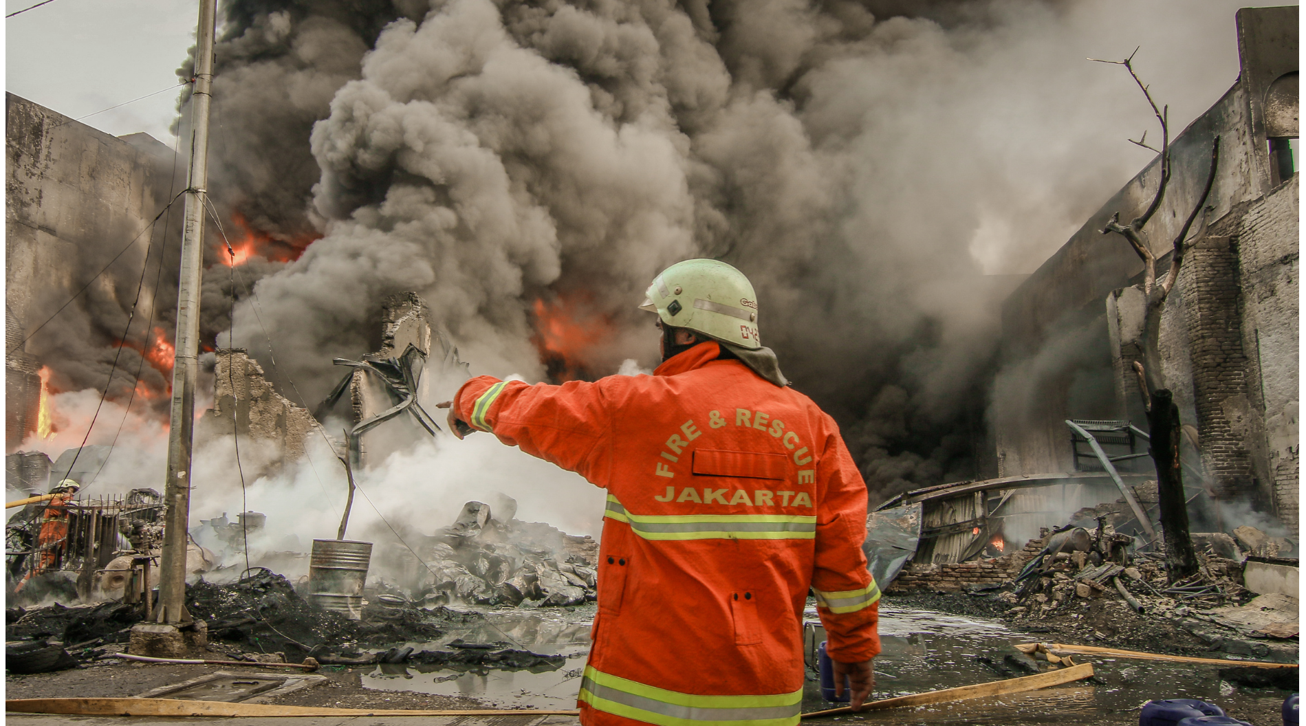A firefighter silhouetted against fire and smoke with a self-powered field unit still running in the blackout